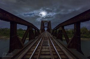 The full moon rises over a train trestle on the Blanco River.