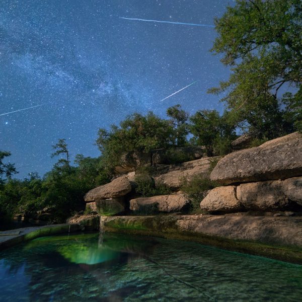 Shooting stars from the Perseid Meteor Shower streak overhead a Jacob's Well.