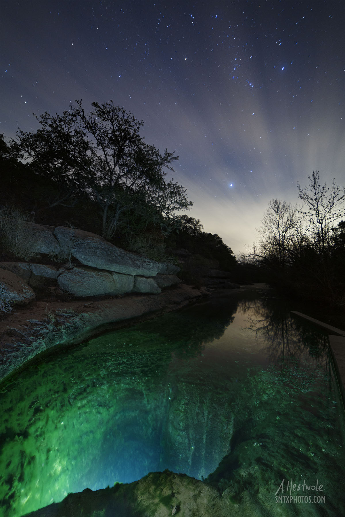 Jacob's Well in Wimberley, TX at night with clouds and stars.